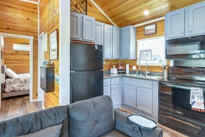 A compact kitchen with grey cabinets, a black refrigerator, and a stove.