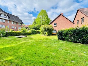 A residential area with a well-maintained lawn, a small play area, and houses with brick facades. - Margaretha Vacation Home (Varel)
