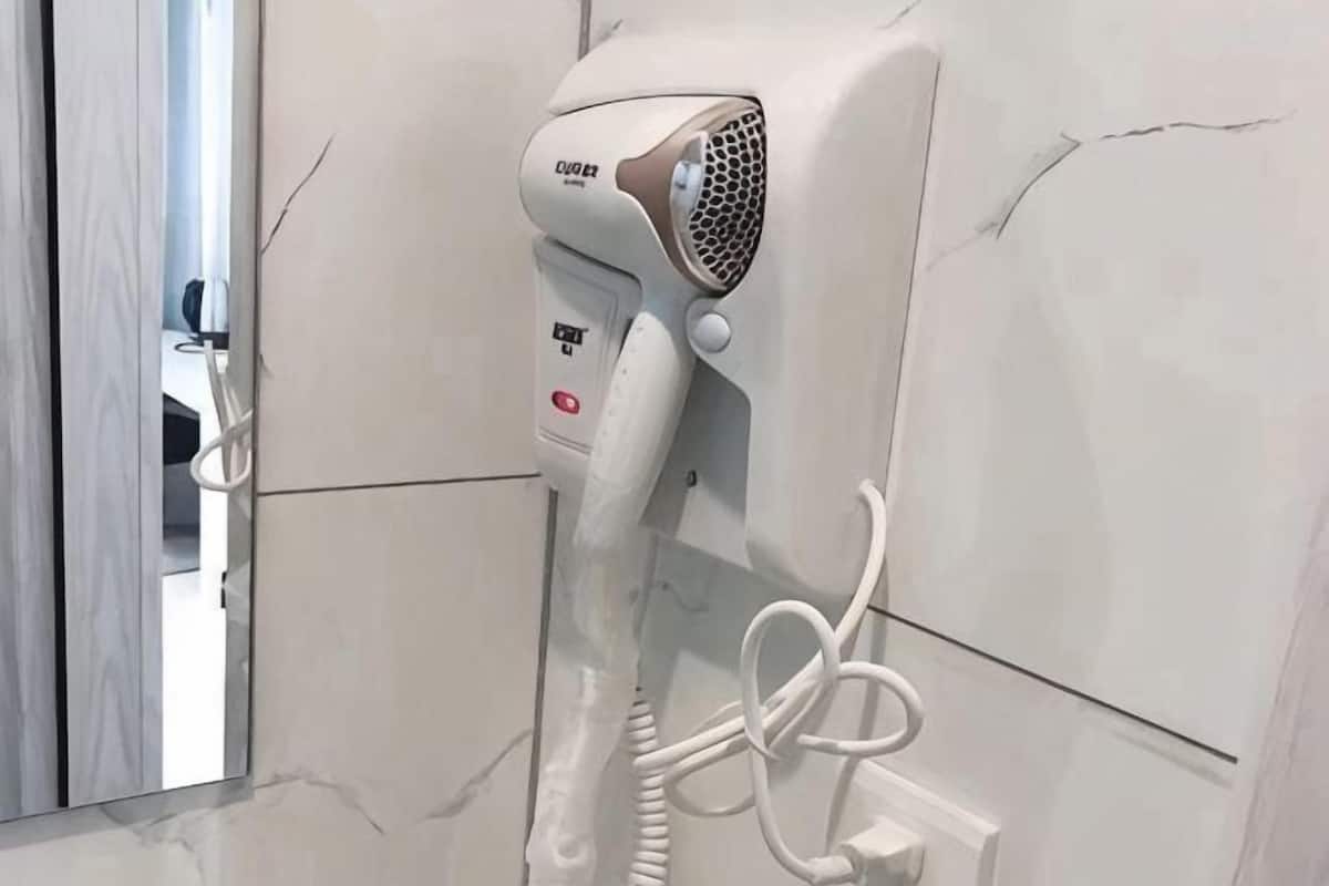Un secador de pelo montado en la pared, con un enchufe a la vista.
