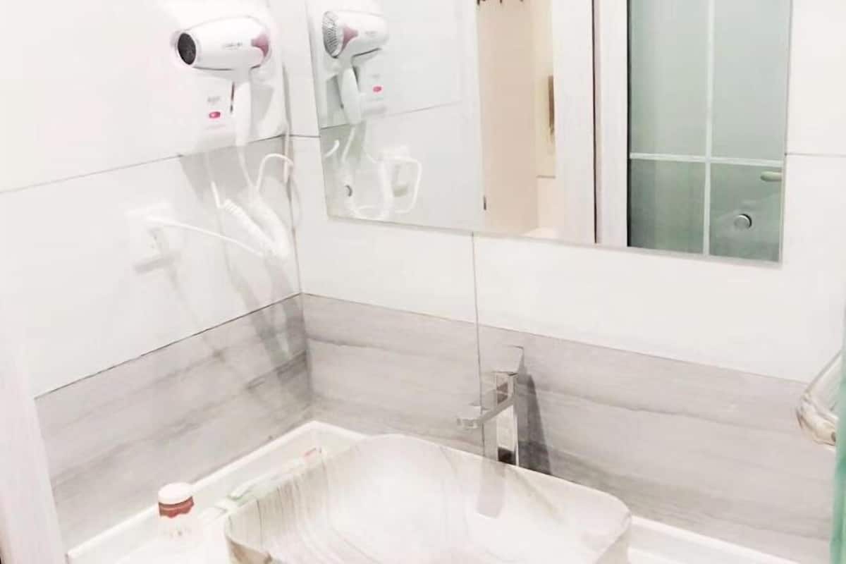 Un baño con espejo, dos secadores de pelo, un perchero para toallas y una botella en la encimera.