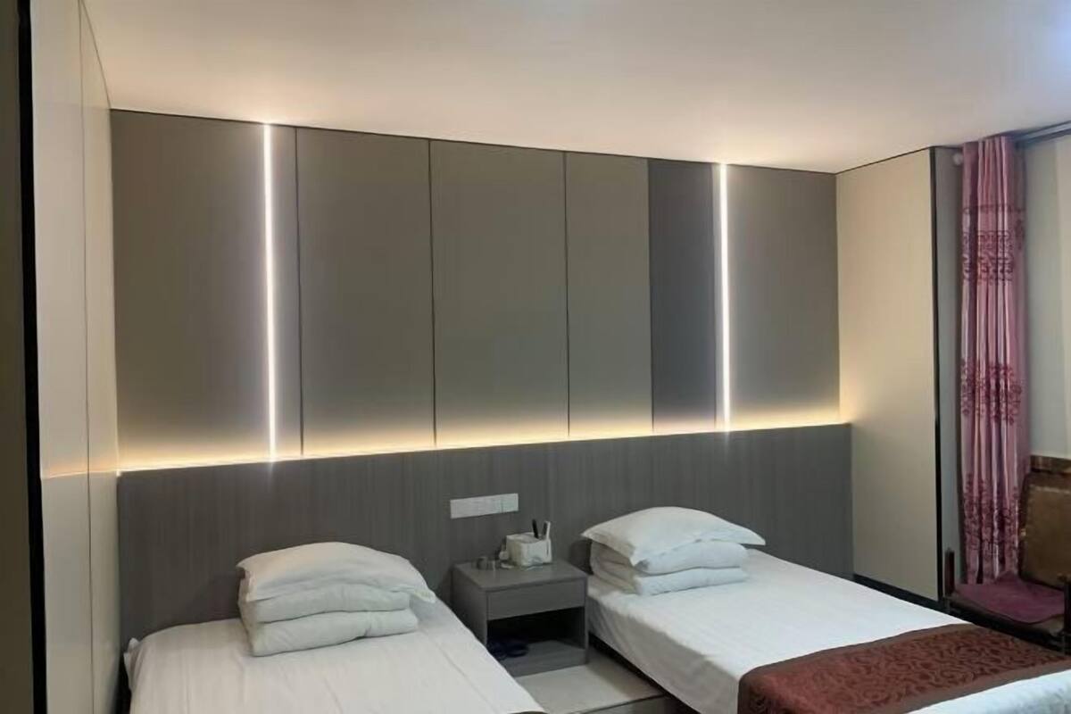 Una habitación de hotel con dos camas, una mesita de noche, un espejo y un armario.