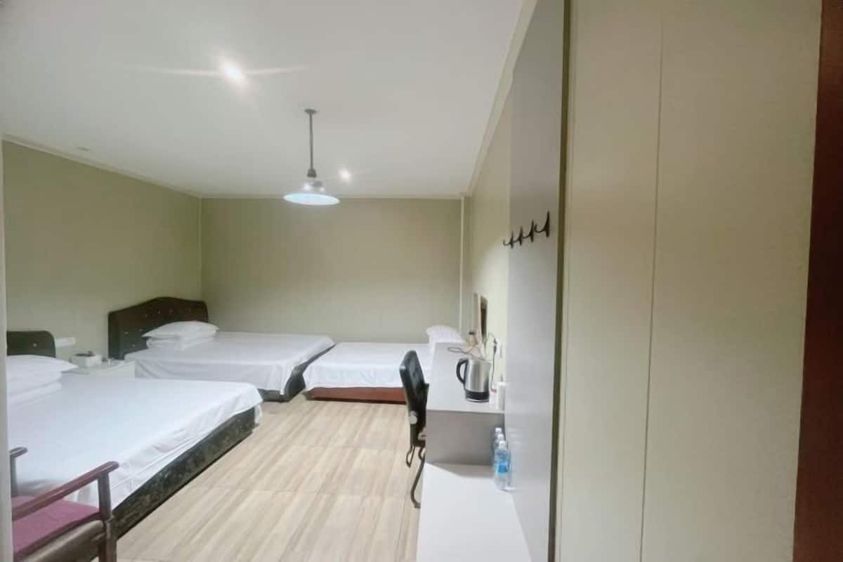 Habitación de hotel con dos camas, un escritorio, una silla, un hervidor y una botella de agua.