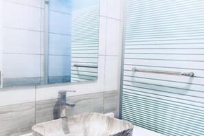 A bathroom with a marble sink, a mirror, and a glass shower enclosure. - Jiuxin Hotel (Jiujiang)