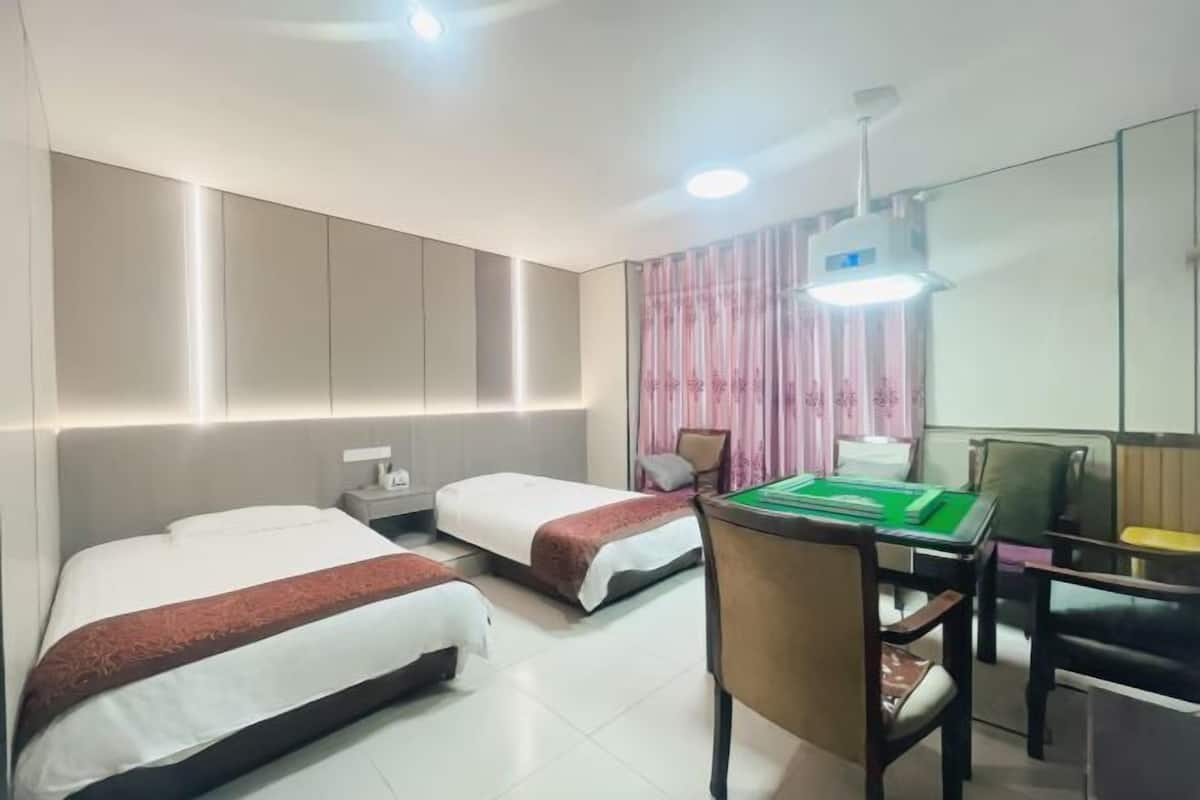 Una habitación de hotel con dos camas, un escritorio con una mesa verde y un espejo.