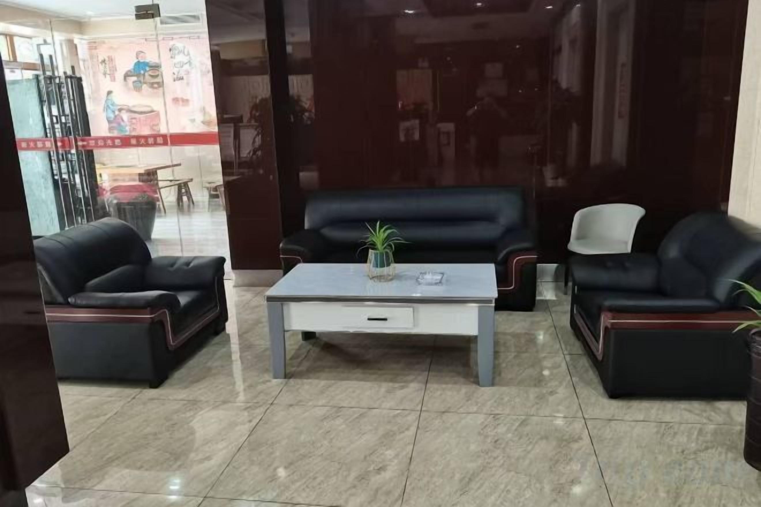 A lobby with a black leather sofa set, a white coffee table, and a glass partition.