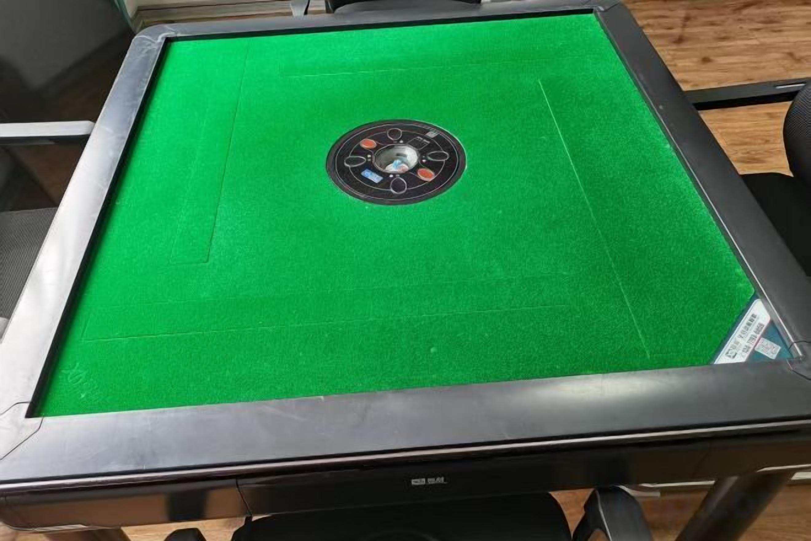 A pool table with a green felt surface and a circular cue ball rack.