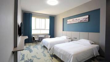 Habitación de hotel con dos camas, un escritorio, una silla y un televisor.