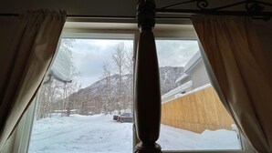 A window with curtains, a view of a snowy landscape, and a mountain in the background. - Alaskan studio in the mountains (Anchorage)