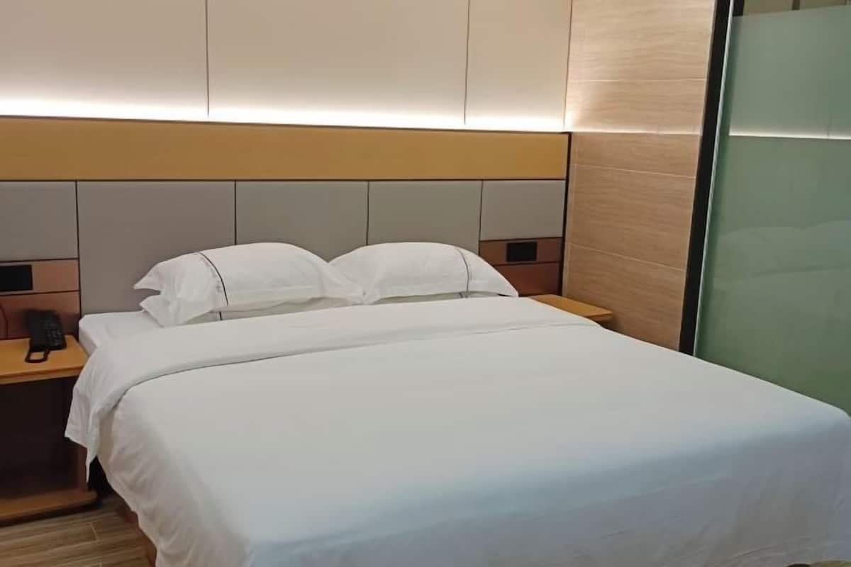 Una habitación de hotel con una cama, mesitas de noche y un teléfono.