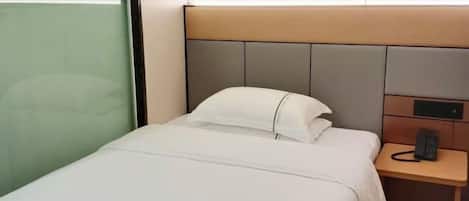 A hotel room with a bed, bedside table, and a phone.