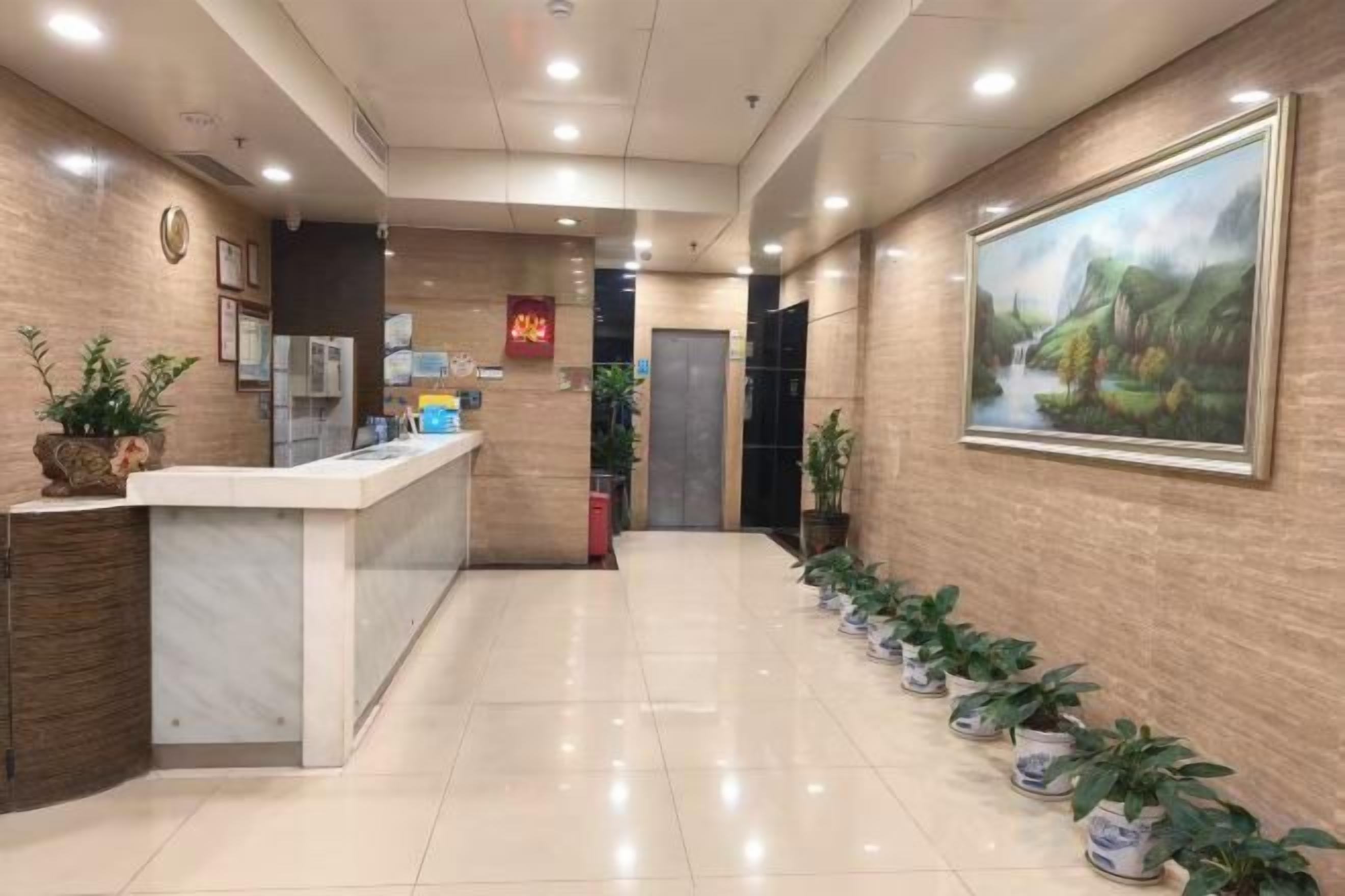 A hotel reception area with a reception desk, a clock, and a framed painting on the wall.