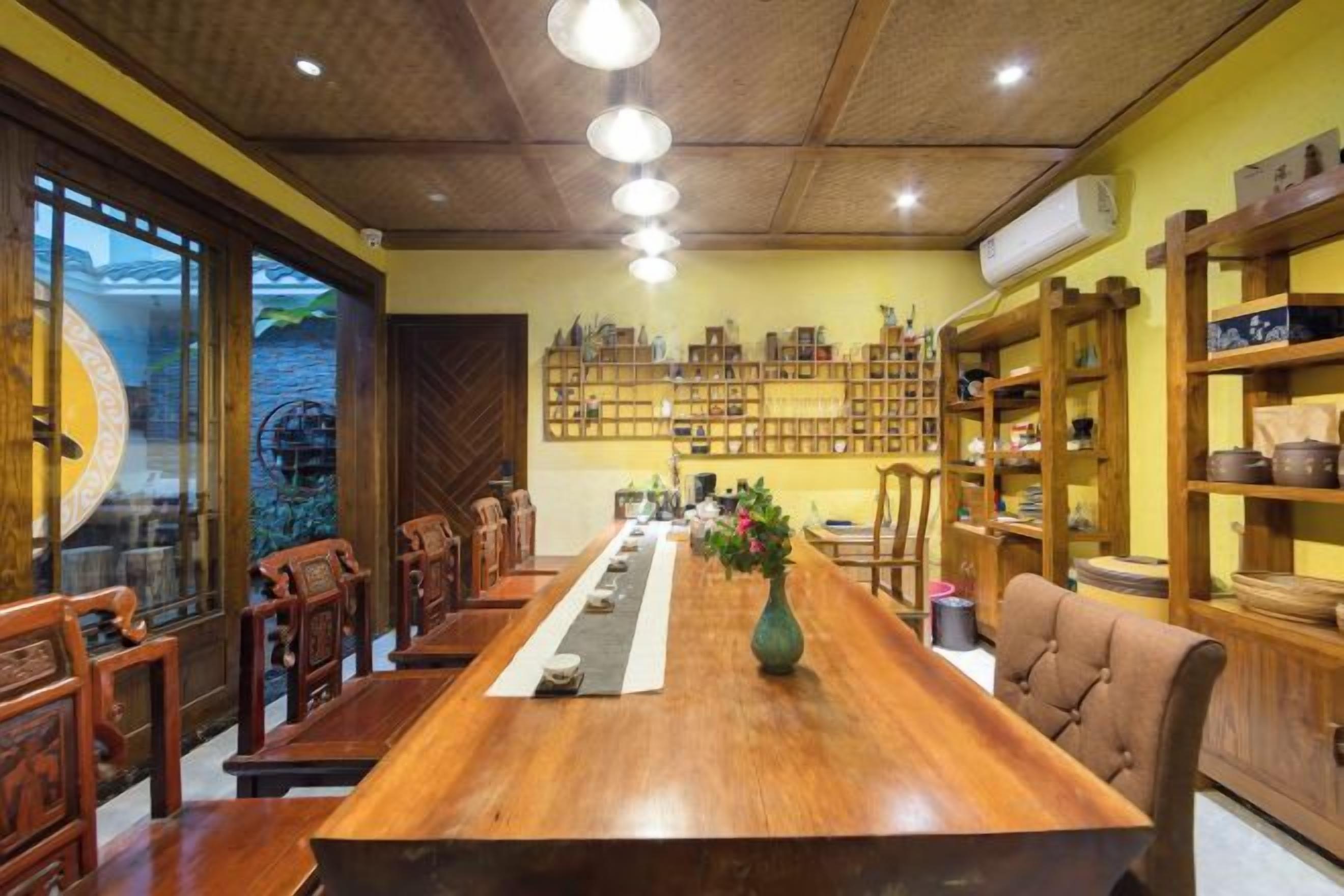A long wooden dining table with chairs, surrounded by shelves with various items.