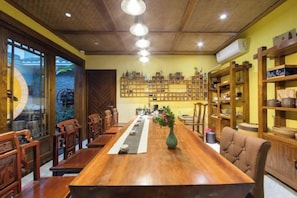 A long wooden dining table with chairs, surrounded by shelves with various items. - Longmen Yihao Inn (Zhangjiajie)