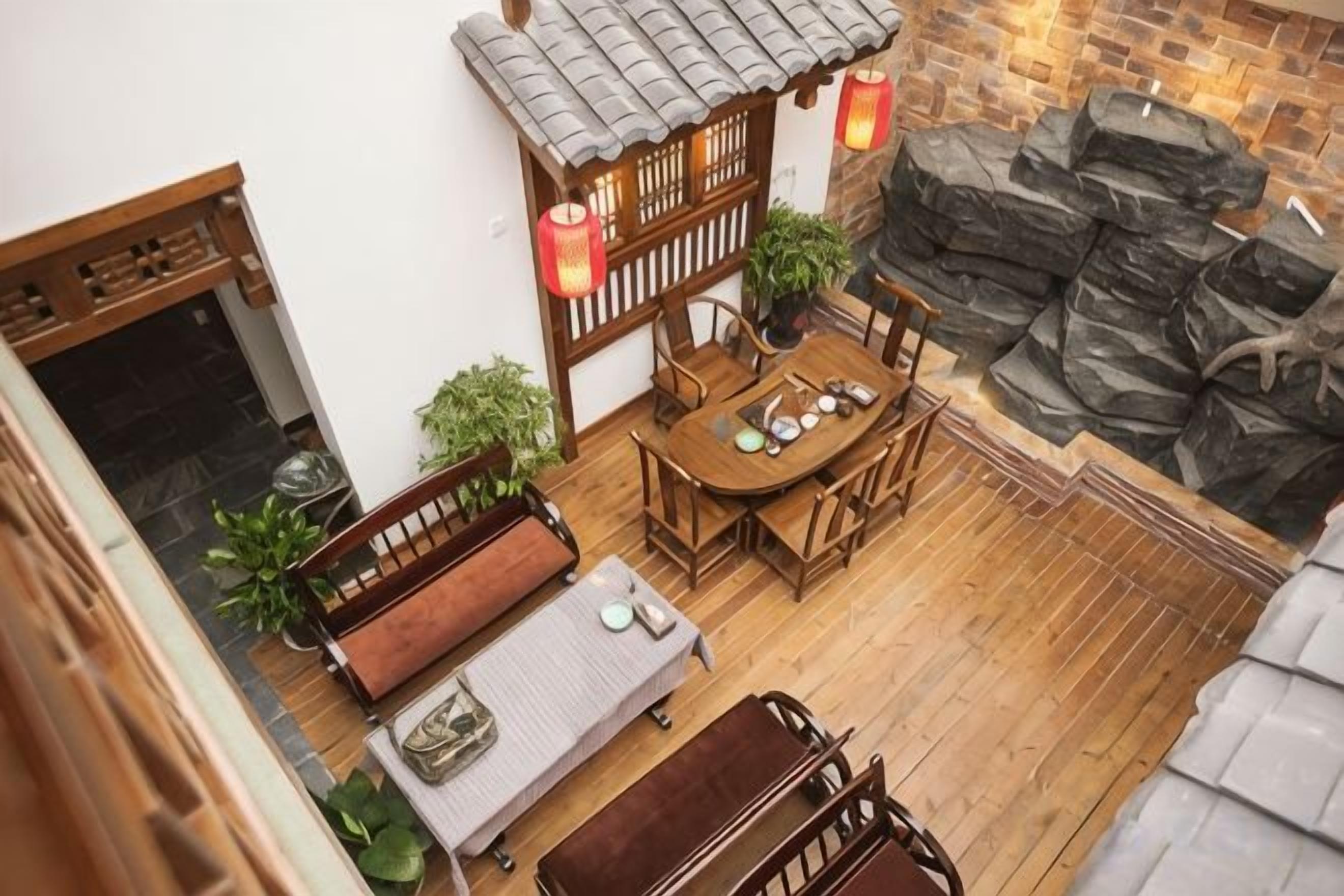 Un espacio al aire libre de estilo tradicional con una mesa de madera y bancos, rodeado de plantas en macetas y un muro de piedra.