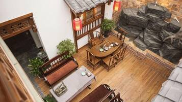 Un espacio al aire libre de estilo tradicional con una mesa de madera y bancos, rodeado de plantas en macetas y un muro de piedra.