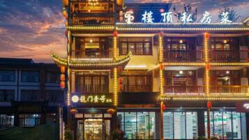 Un edificio de varios pisos con elementos arquitectónicos tradicionales, incluyendo una entrada al estilo pagoda y señalización iluminada.