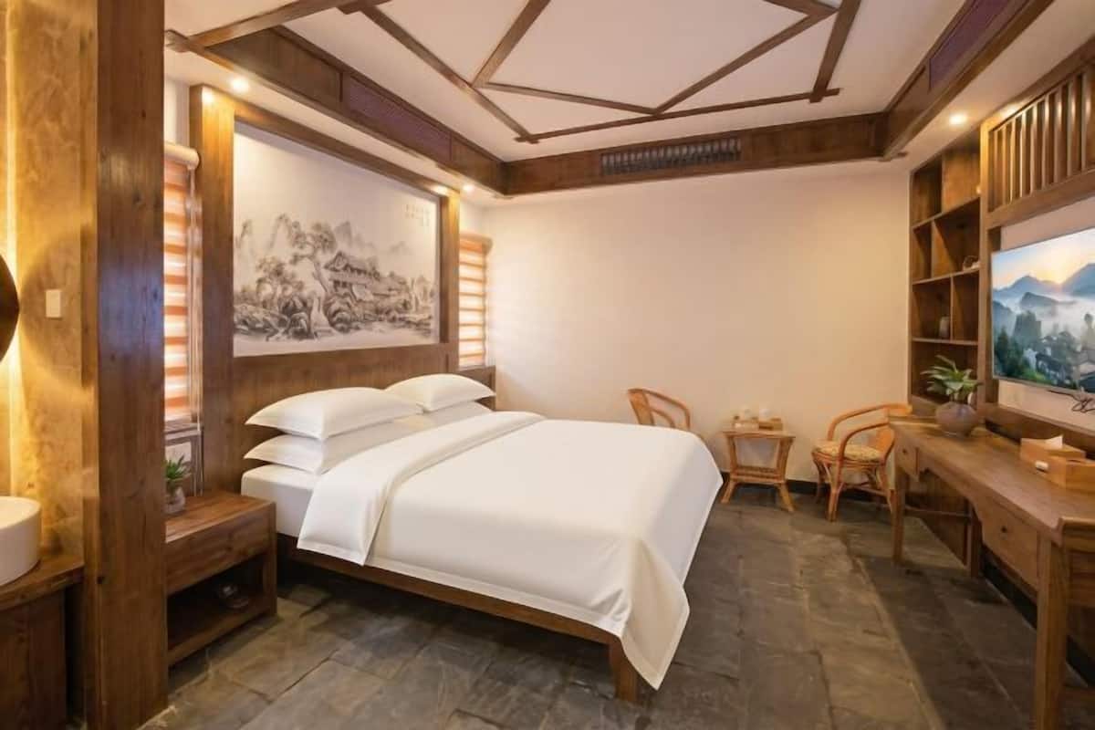Une chambre à coucher comprenant un lit, des tables de chevet, un bureau, des chaises et des œuvres d’art accrochées aux murs.