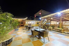 An outdoor dining area with tables and chairs, a covered seating area, and a staircase leading to an upper level. - Longmen Yihao Inn (Zhangjiajie)