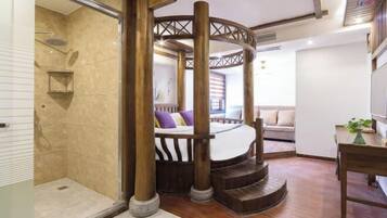 A room with a circular wooden structure, a bed with striped bedding, and a small table with a plant.