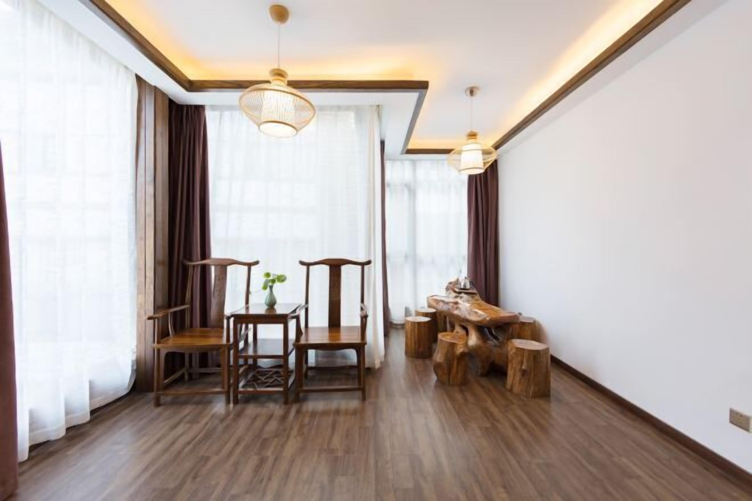 A spacious room with a wooden floor, a dining table with chairs, a wooden bench, and a hanging light fixture.