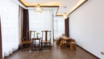 A spacious room with a wooden floor, a dining table with chairs, a wooden bench, and a hanging light fixture.