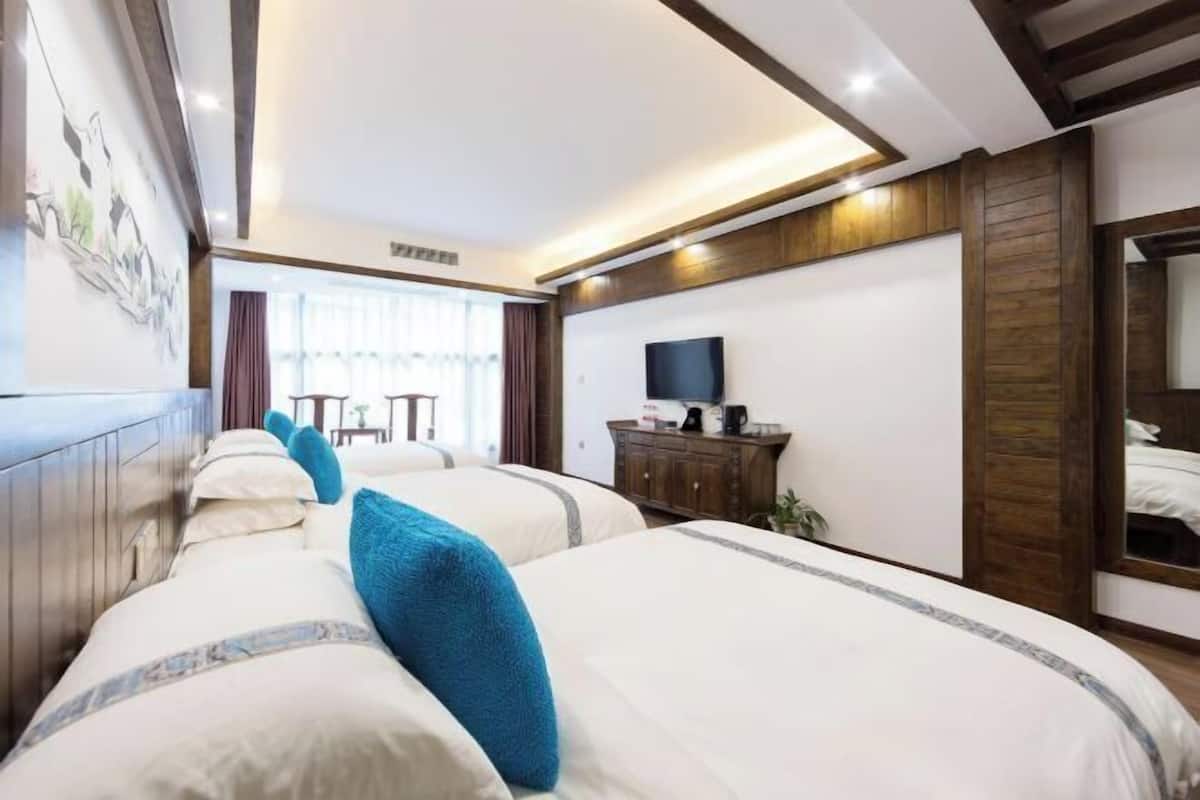 Une chambre d’hôtel avec deux lits, une télévision, une armoire en bois et une grande fenêtre.