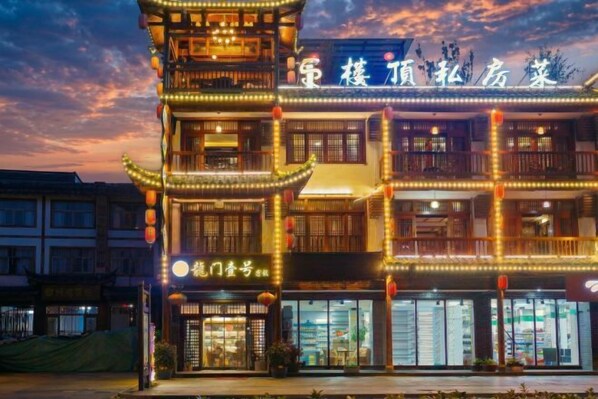 A traditional multi-story building with illuminated signage and balconies, likely a hotel or guesthouse.