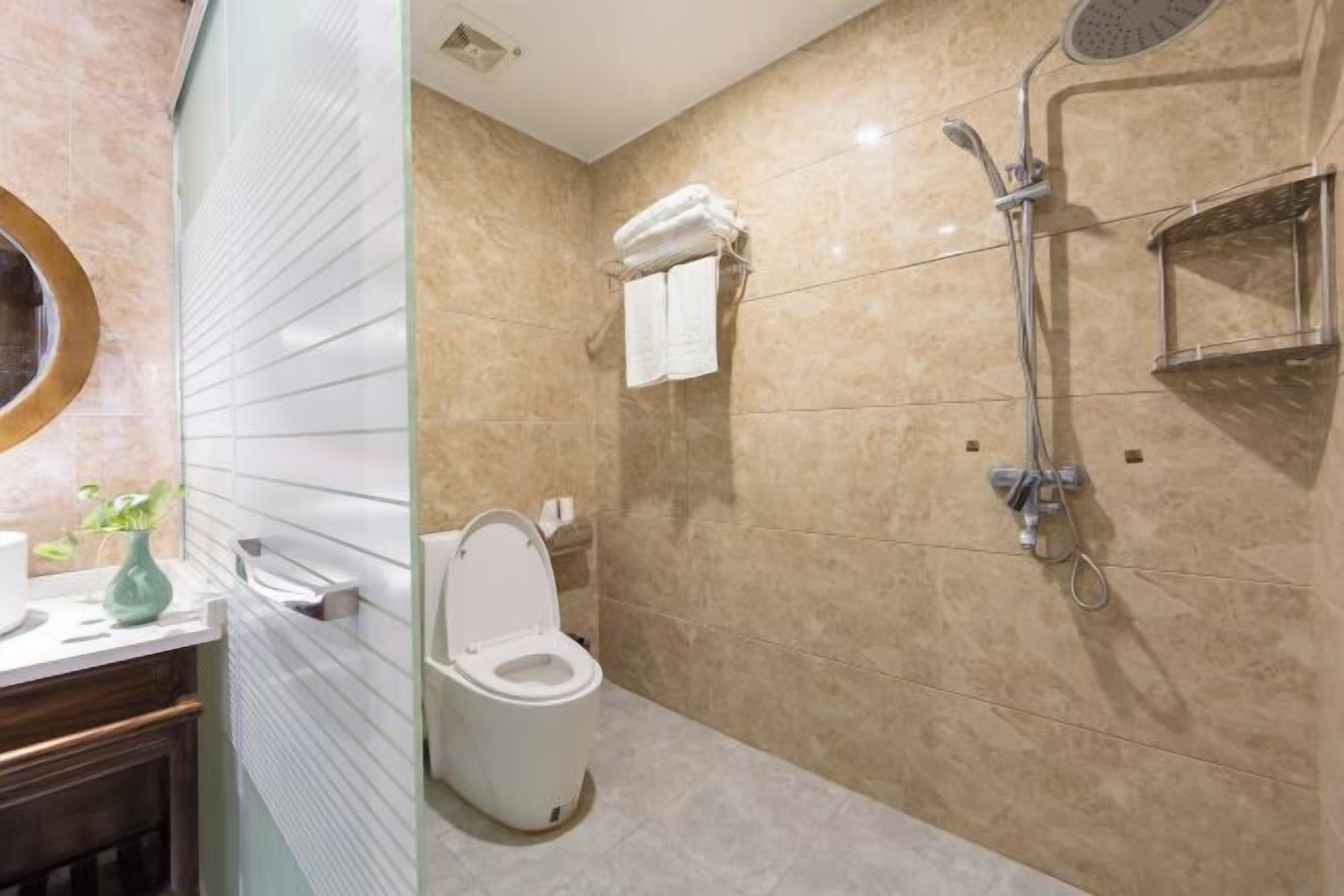 A modern bathroom with a toilet, shower, and a towel rack.