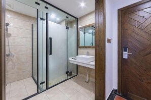 A modern bathroom with a glass shower enclosure, a white sink, and a wooden door. - Longmen Yihao Inn (Zhangjiajie)