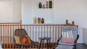 En balkong med två stolar, ett litet bord och en hylla med dekorativa föremål.