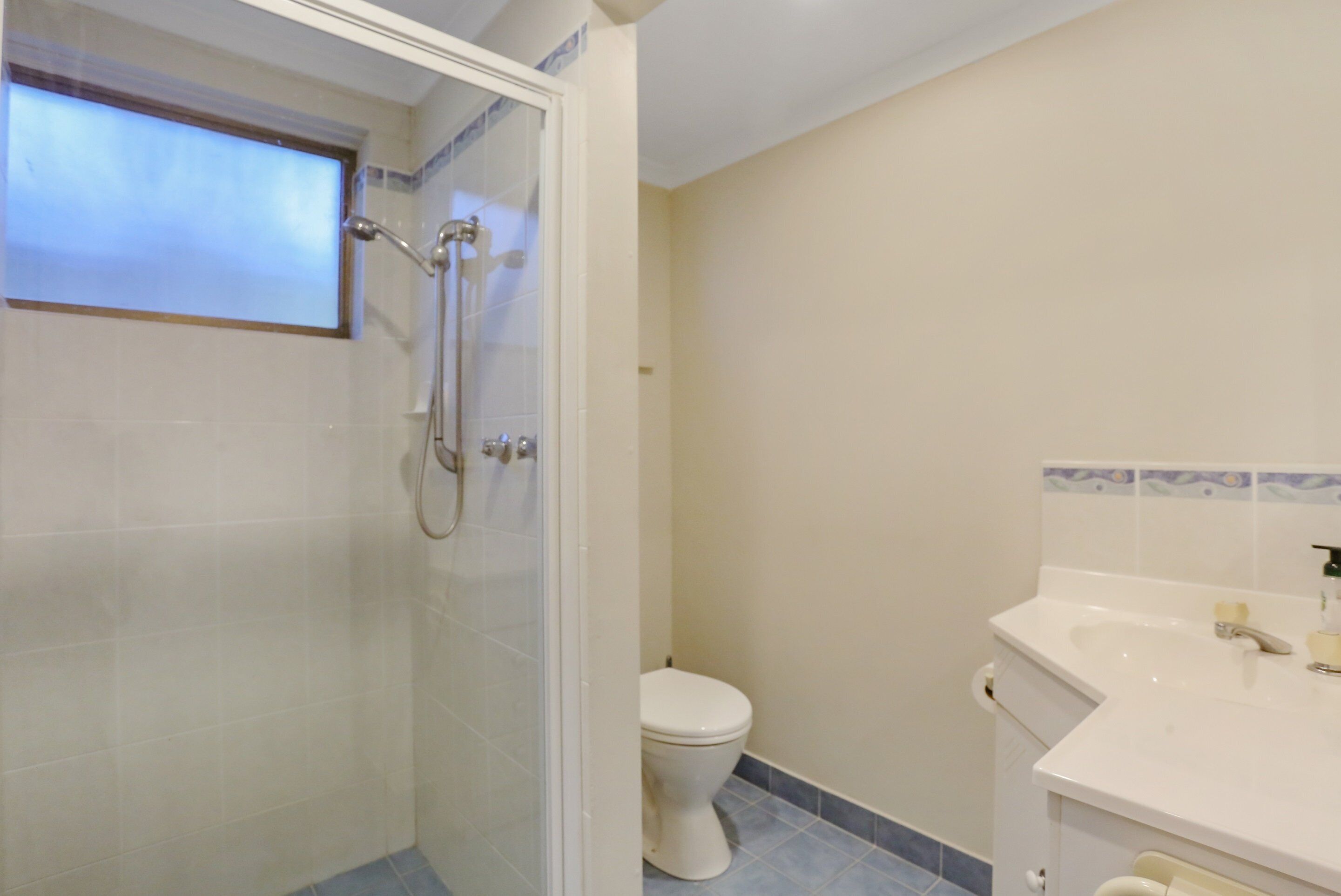 A bathroom with a shower, toilet, and sink.