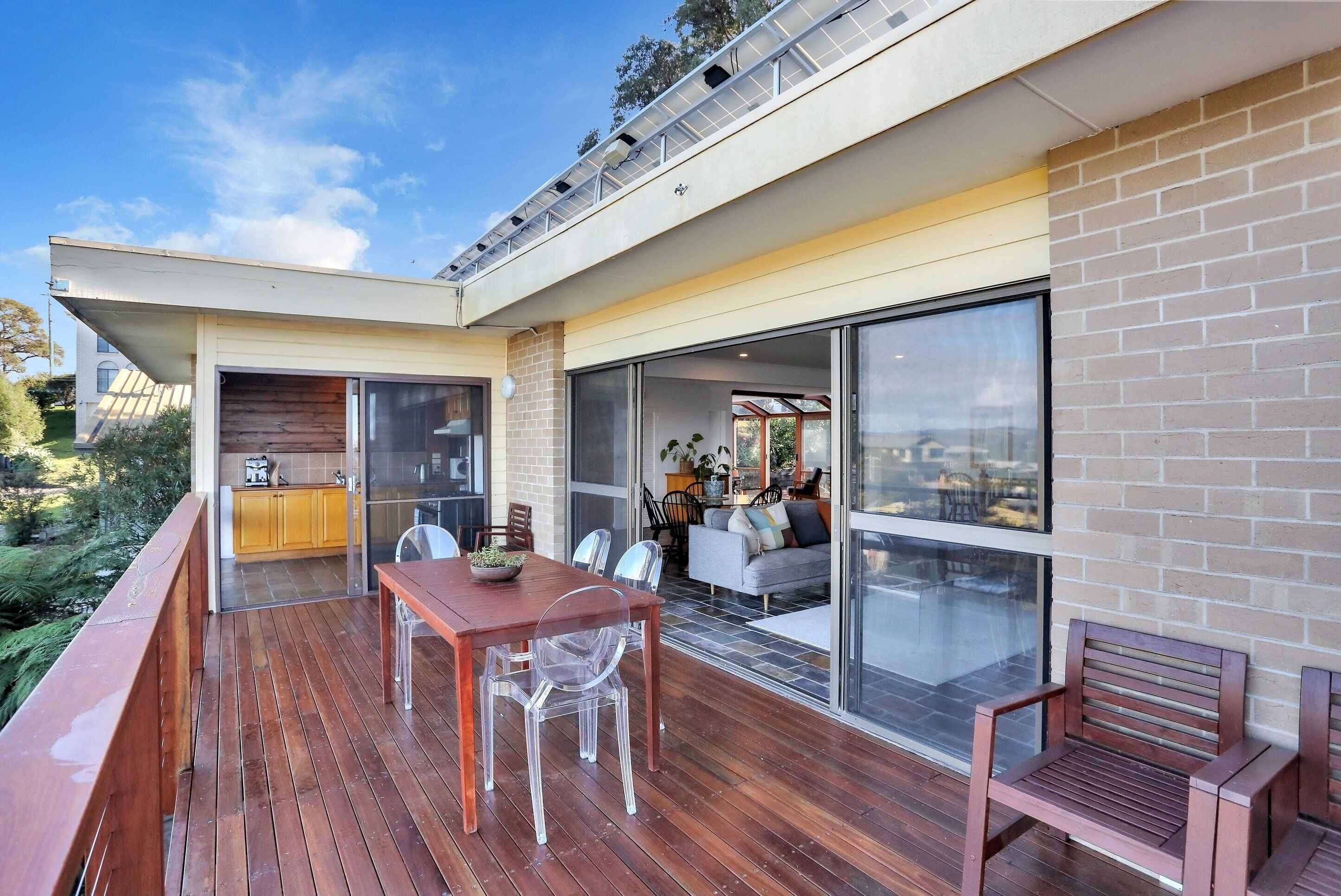 A modern outdoor deck with a wooden table and chairs, a sofa, and a bench.