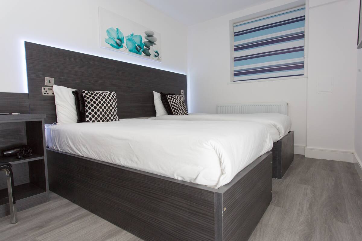 A modern bedroom with a large bed, a built-in desk, and a radiator.