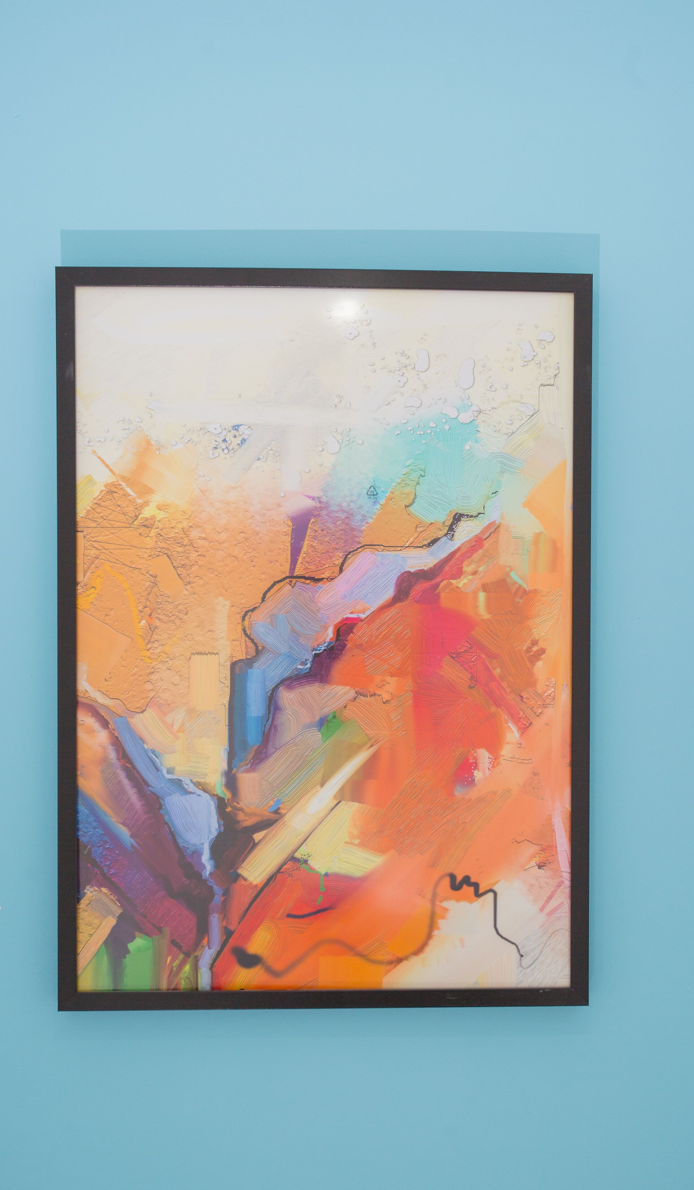 Een lijst met een abstract schilderij, met een mix van kleuren en texturen.