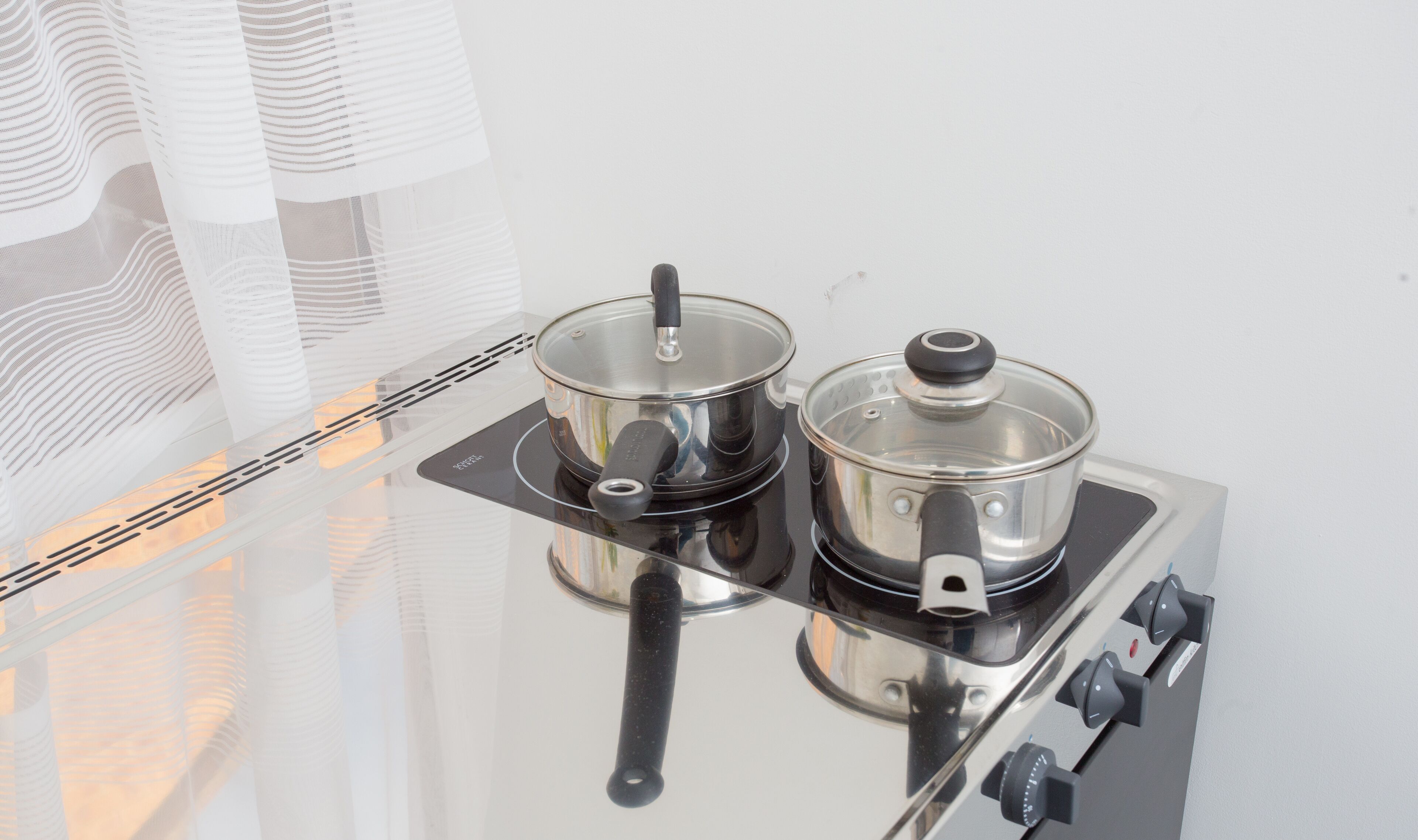 A kitchen with two stainless steel pots on a stove.
