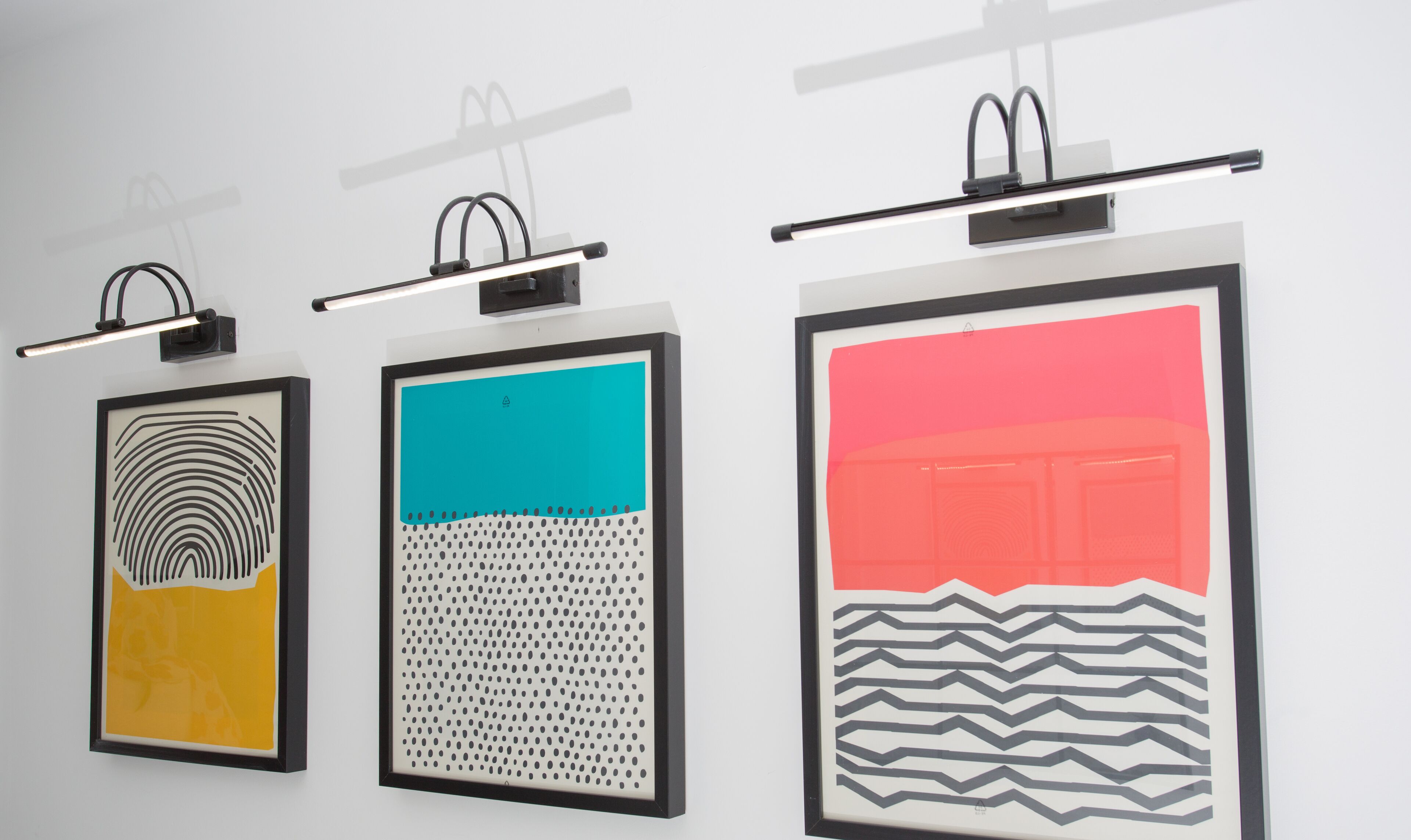 Three framed artworks on a wall, each with a unique pattern and color scheme.