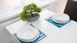 A dining table set with plates, cutlery, and a bonsai tree. - Heathrow Windsor Apart Hotel  (Slough)