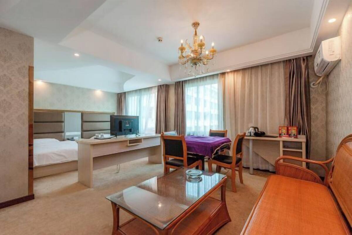 Een hotelkamer met een bed, een bureau met een computer, een eettafel en een bank.