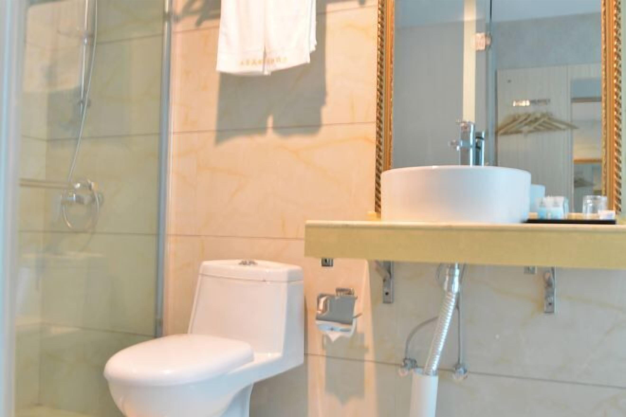 Un baño con cabina de ducha de vidrio, inodoro blanco y lavabo con espejo.