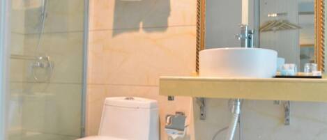 Un baño con cabina de ducha de vidrio, inodoro blanco y lavabo con espejo.