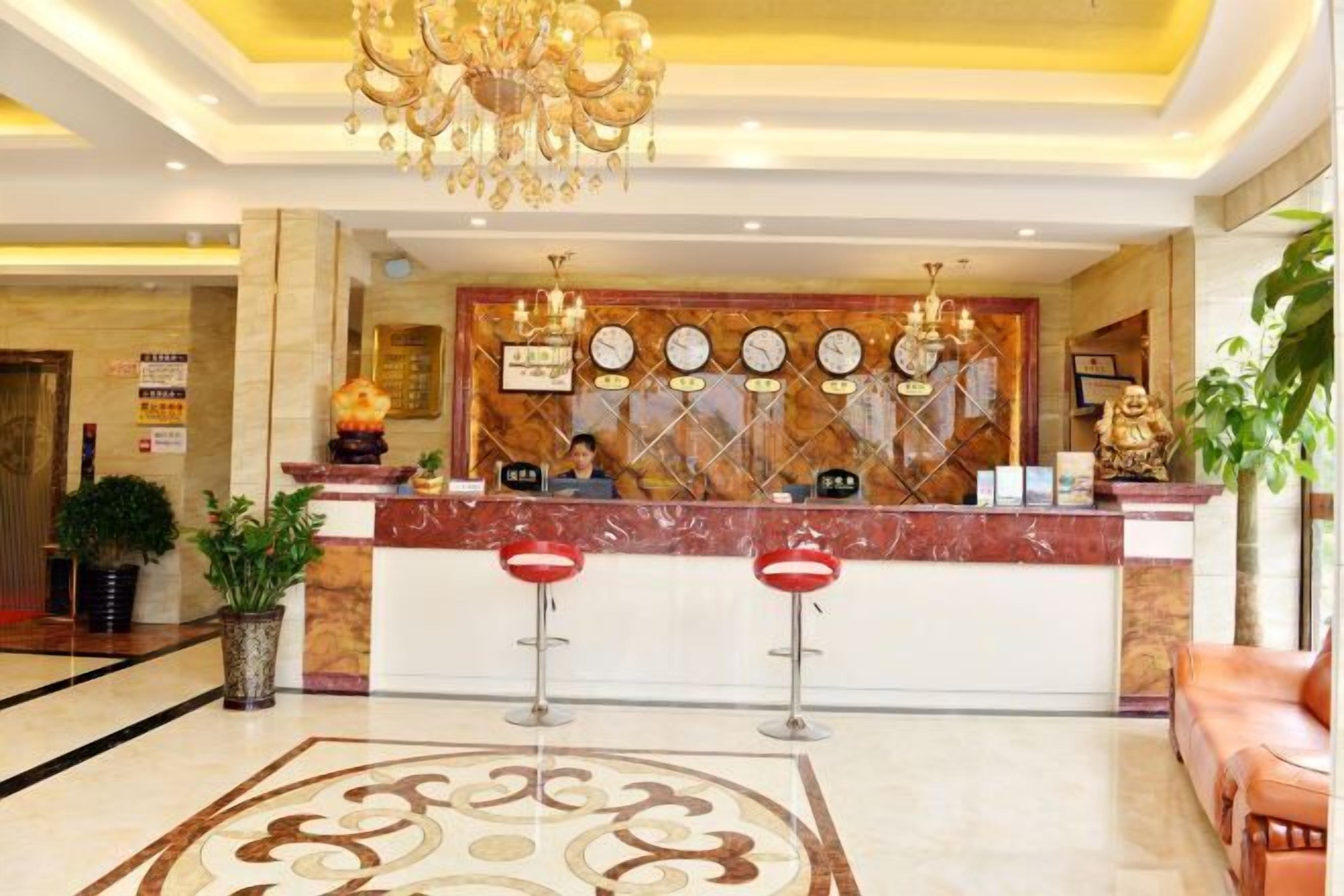 A hotel reception area with a marble counter, a chandelier, and a reception desk.