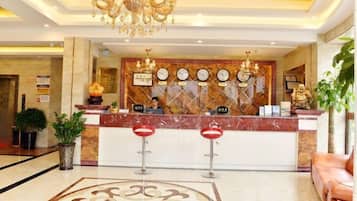 A hotel reception area with a marble counter, a chandelier, and a reception desk.
