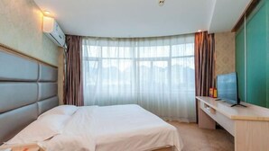 Une chambre d’hôtel avec un lit, un bureau, une télévision et une fenêtre avec des rideaux.