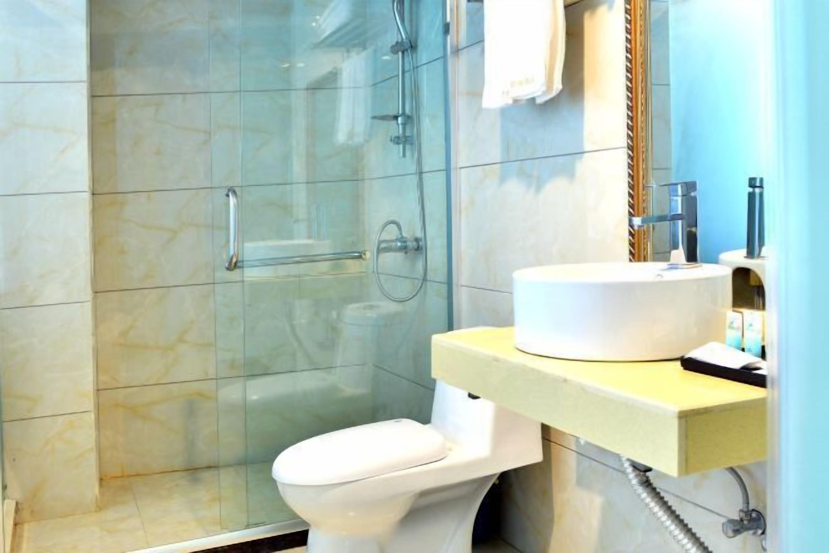 A bathroom with a glass shower enclosure, a white toilet, and a sink with a mirror above it.