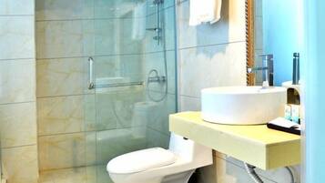 A bathroom with a glass shower enclosure, a white toilet, and a sink with a mirror above it.