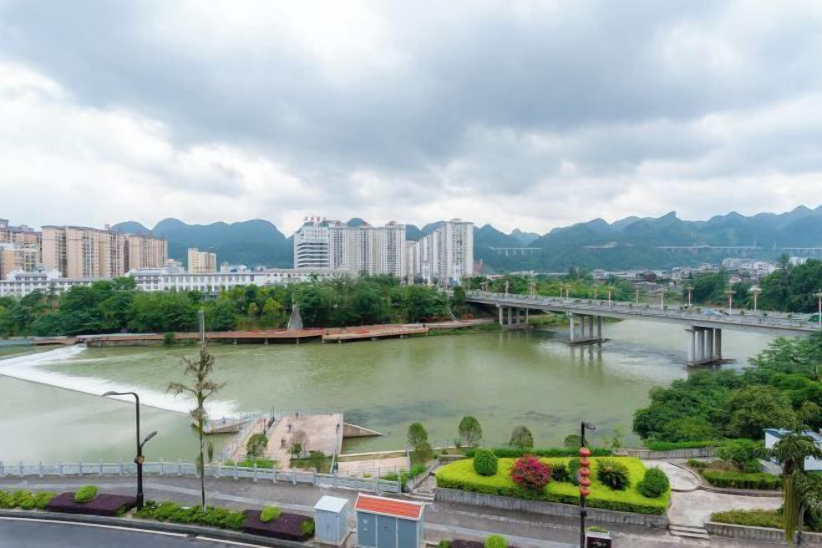 Un río con un puente, rodeado de vegetación y edificios.