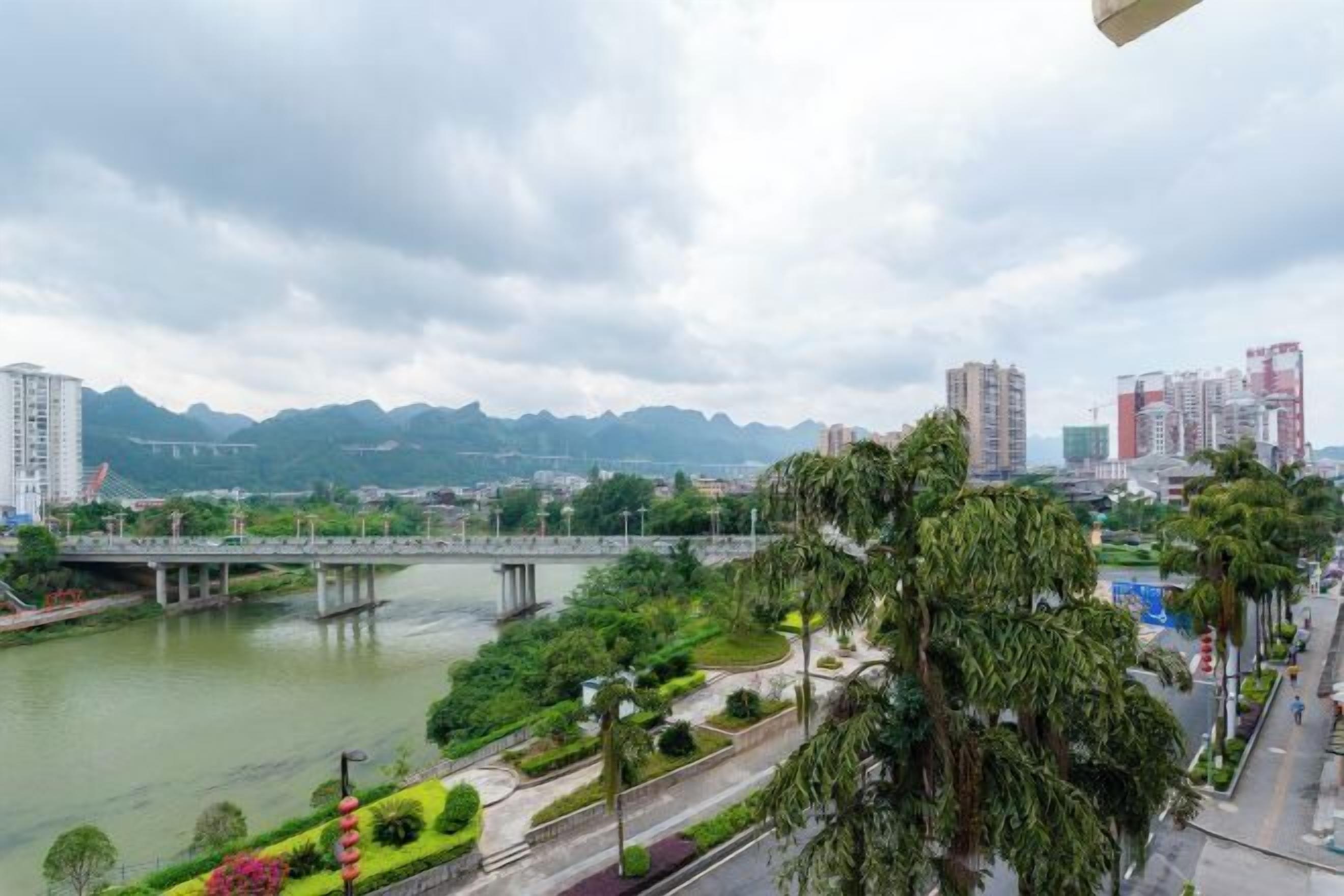 A cityscape with a river, a bridge, and mountains in the background.