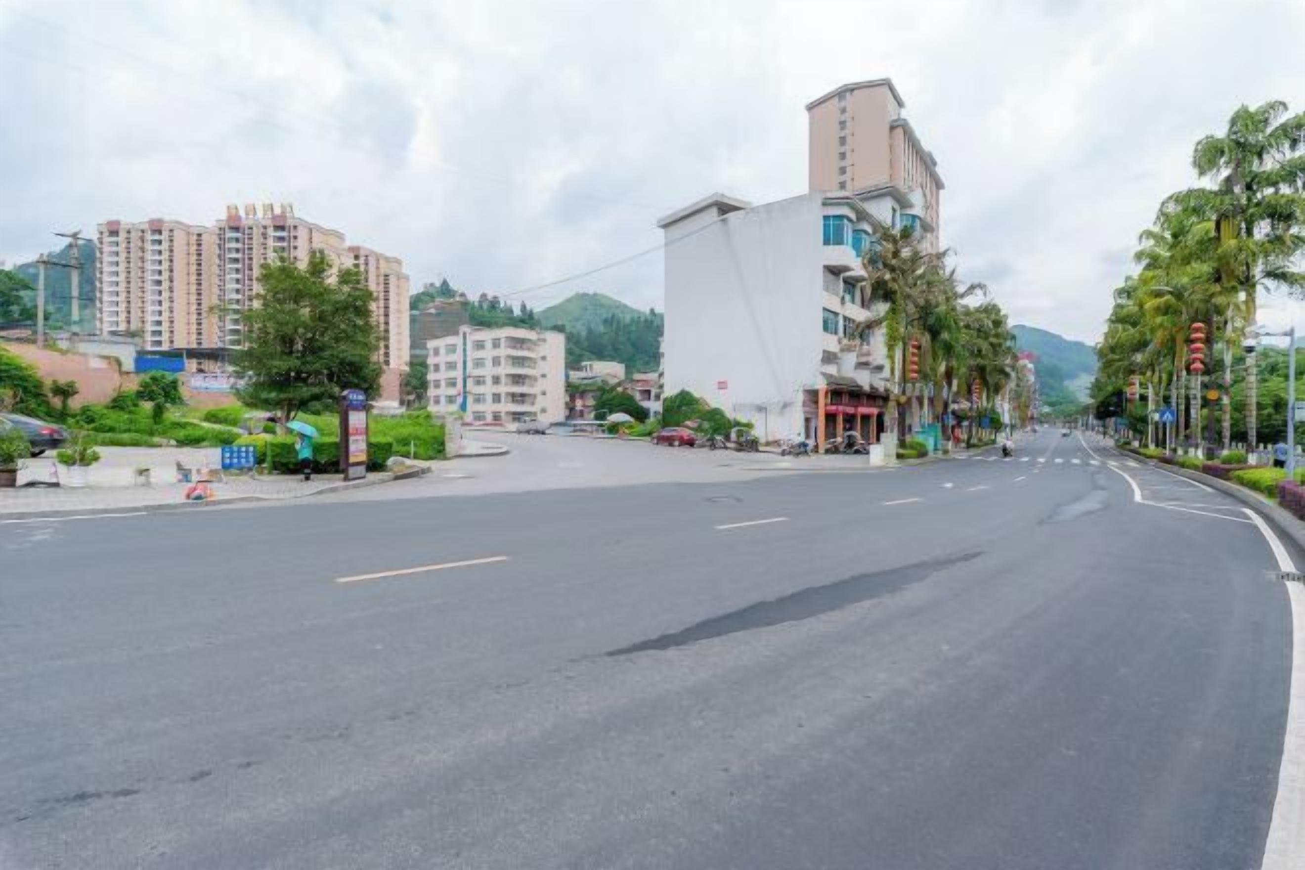 Une large route dégagée, bordée de bâtiments modernes des deux côtés, dont un imposant bâtiment blanc à la façade incurvée.