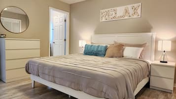 Un dormitorio con cama, mesitas de noche, un espejo y una puerta.