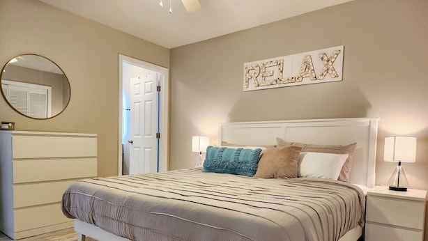 A bedroom with a bed, bedside tables, a mirror, and a door.